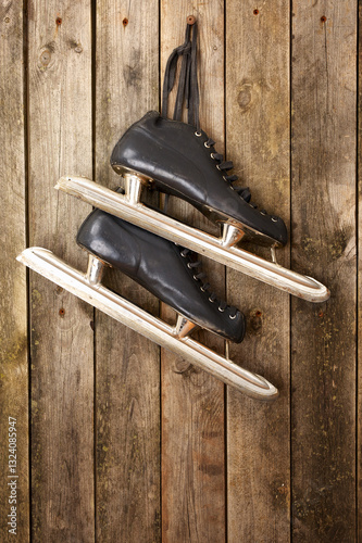 Pair of skates hanging from laces on a rustic wooden wall