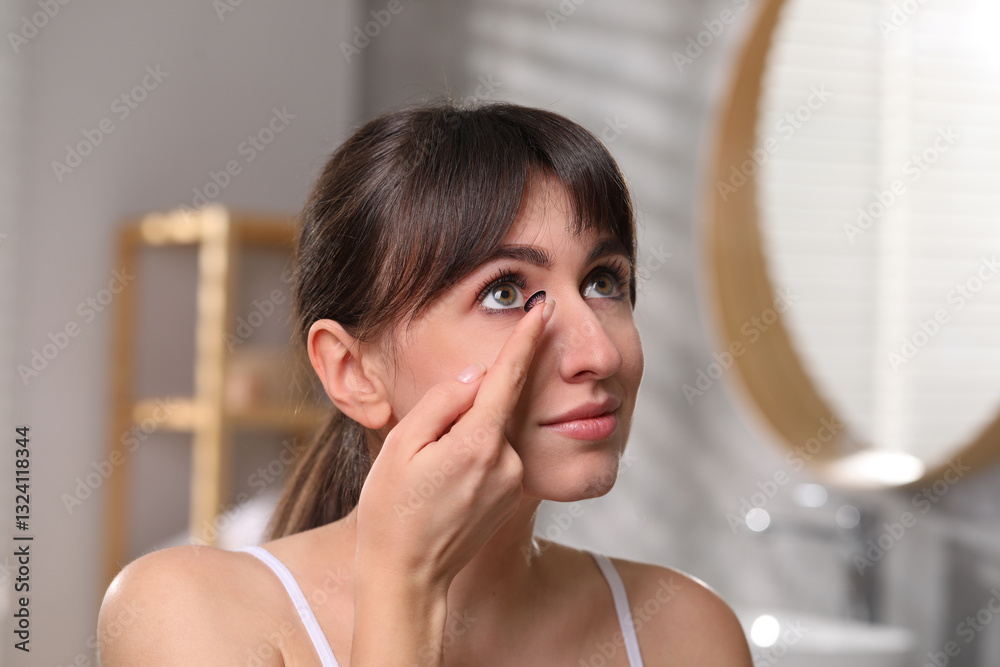 Young woman putting in color contact lens in bathroom Young woman putting in color contact lens in bathroom