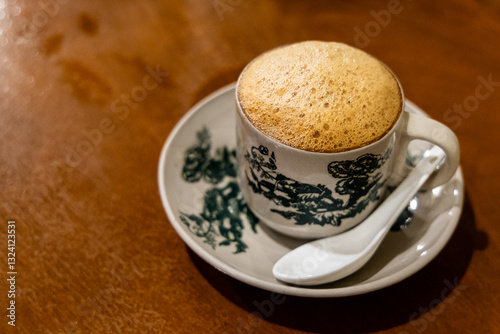 Popular traditional aromatic frothy coffee with milk served in retro cup and saucer at kopitiam in Malaysia