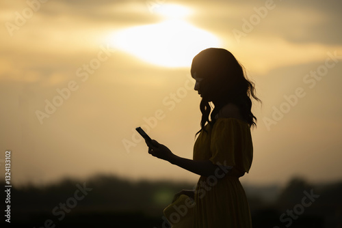 Silhouette of Happy beautiful young woman having smartphone conversation, feeling energized by Beautiful sunrise sky above clouds with dramatic light. Enjoying nature, sunset or sunrise. Freedom.