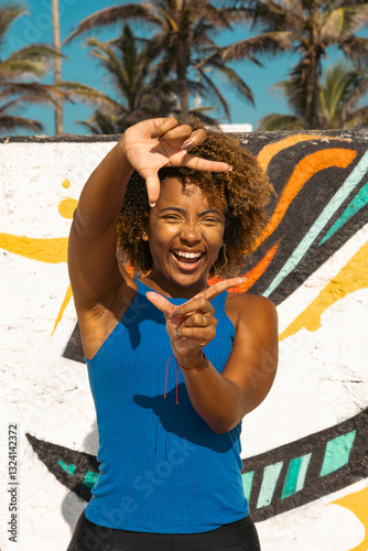 Beautiful young  woman over grafitti background Smiling doing frame using hands palms and fingers, camera perspective.