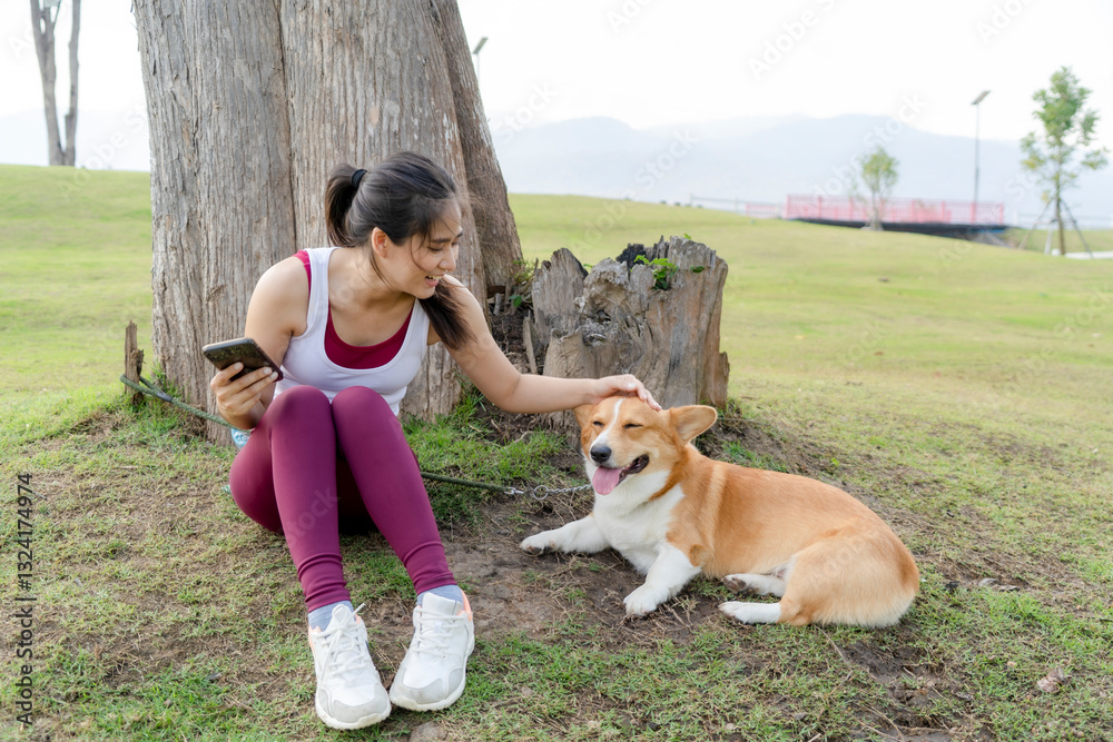 Obraz premium A woman is sitting on the grass next to a dog