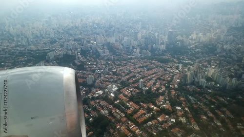View through the airplane window during a flight over the city of São Paulo, passing over the Vila Madalena and Pinheiros region on the way to Congonhas airport.
