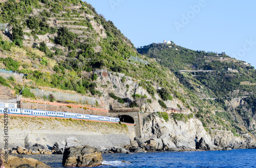 An Italian Railways train enters a tunnel. The section of railway on the mountainside between Manarola and Riomaggiore, Cinque Terre, view from the sea
