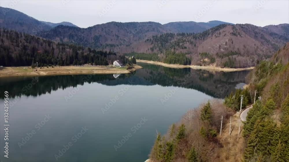Drone scenic view of a serene body of water surrounded by forests and mountains Drone scenic view of a serene body of water surrounded by forests and mountains