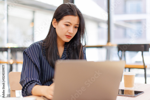Free Download Portrait of Business Asian woman sitting at at laptop and thinking of problem solution, working schedule for employee writing report into notebook while using laptop computer in coworking space	 - GFXLoad
