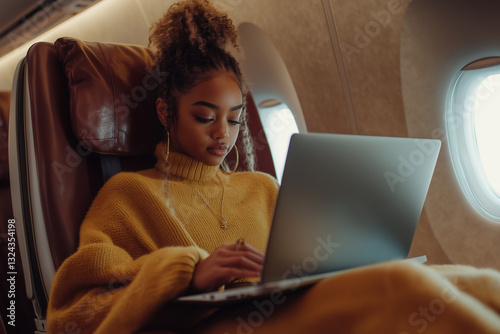 A stylish young woman works on her laptop while traveling in a luxurious airplane cabin.  Suitable for topics about freelancing, online work, rich life, travel.