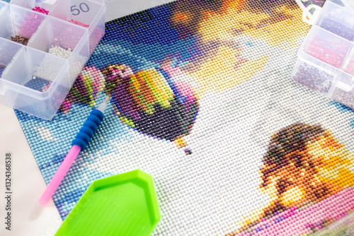 Close-up of a diamond painting and the tools needed to assemble it. Art therapy concept.