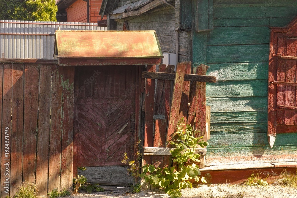 Old wooden fence door at the entrance to the yard of an old wooden house