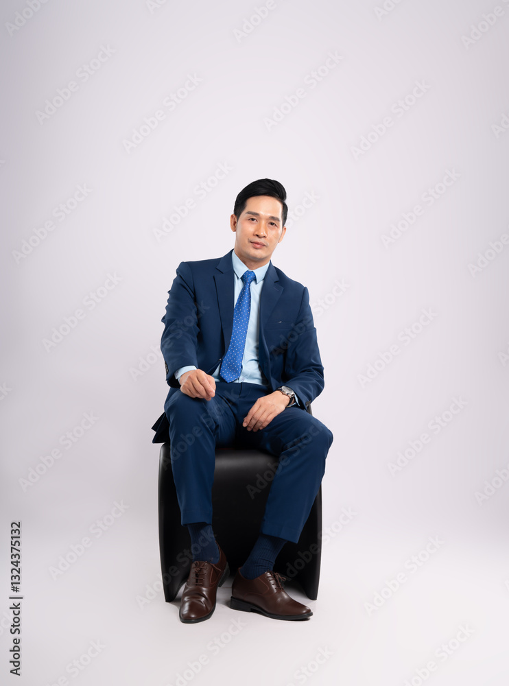 Full body image of Asian male businessman wearing a suit sitting on a chair and posing on a white background Full body image of Asian male businessman wearing a suit sitting on a chair and posing on a white background