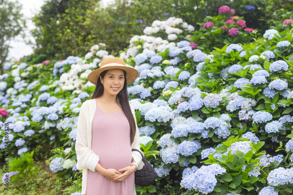 Happy pregnant woman in a colorful flower garden