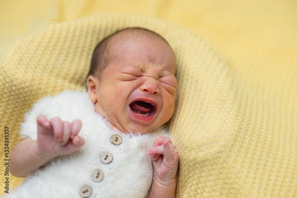 Newborn baby crying loudly while lying in bed