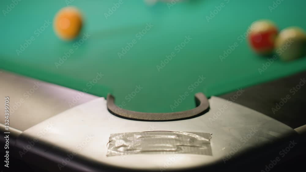 Blurred view of white billiard ball rolling across green pool table, striking green ball, and sinking into pocket. Focus on edge of table and pocket, highlighting motion, strategy Blurred view of white billiard ball rolling across green pool table, striking green ball, and sinking into pocket. Focus on edge of table and pocket, highlighting motion, strategy