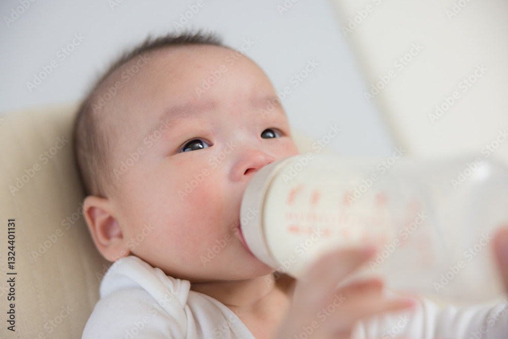 Infant drinking from bottle with parent hand