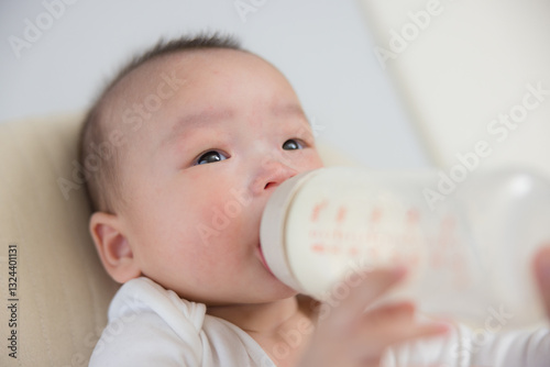 Infant drinking from bottle with parent hand