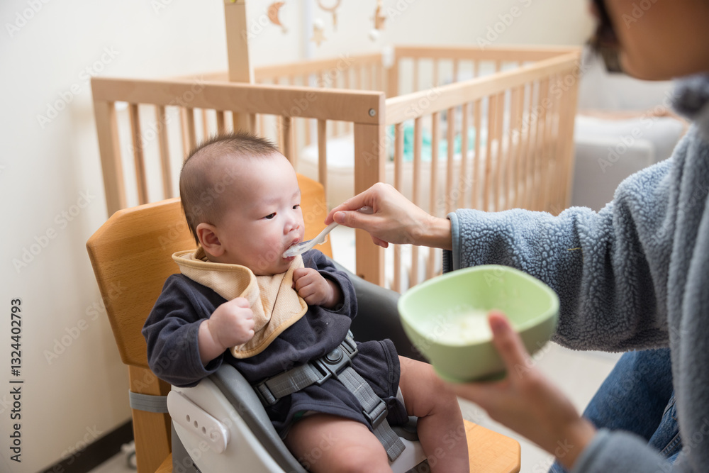Baby Eating Solid Food While Mother Feeds With Spoon