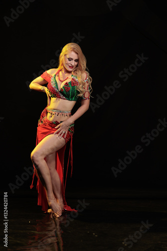 Fotografía Dancer girl with long hair in red oriental costume posing and dancing on black b