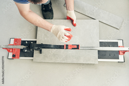 An installation for cutting large ceramic tiles into smaller tiles with precise dimensions. Close-up of the master cutting the tile into two parts with a machine. High quality photo