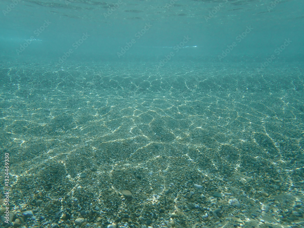 Dark blue ocean surface seen from underwater. Abstract waves underwater and rays of sunlight shining through, Sun light rays undersea deep, Underwater background with sea bottom, Mediterranean sea. Dark blue ocean surface seen from underwater. Abstract waves underwater and rays of sunlight shining through, Sun light rays undersea deep, Underwater background with sea bottom, Mediterranean sea.