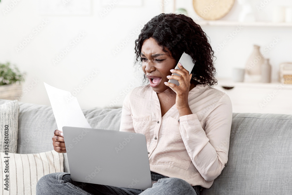 Remote Work Stress. Angry black woman having problems working with laptop and papers at home, checking documents and emotionally talking on cellphone, sitting on couch in living room, free space Remote Work Stress. Angry black woman having problems working with laptop and papers at home, checking documents and emotionally talking on cellphone, sitting on couch in living room, free space