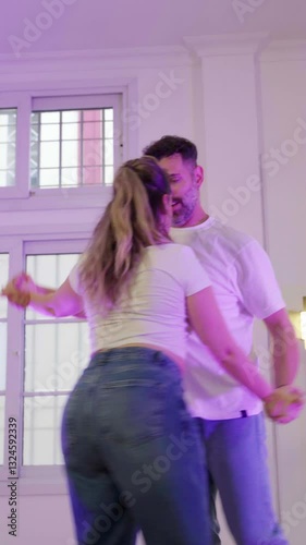 Couple performing bachata dance in studio with purple lighting