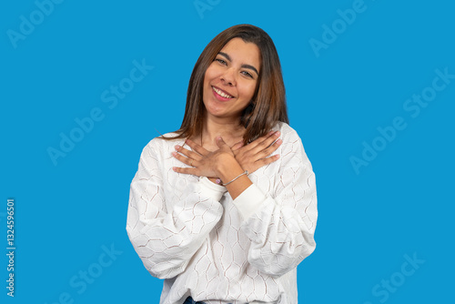 Young latin woman expressing gratitude and hope with hands on chest