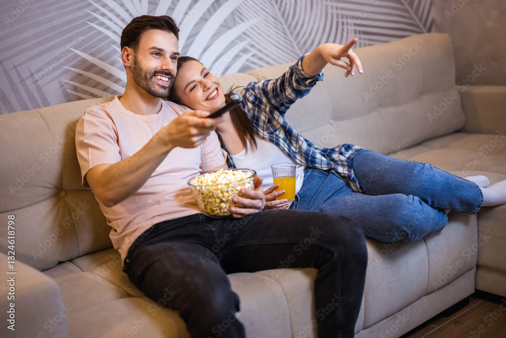 Couple laying on the couch of their living room and watches movies. They eat popcorn and drink juice. Couple laying on the couch of their living room and watches movies. They eat popcorn and drink juice.