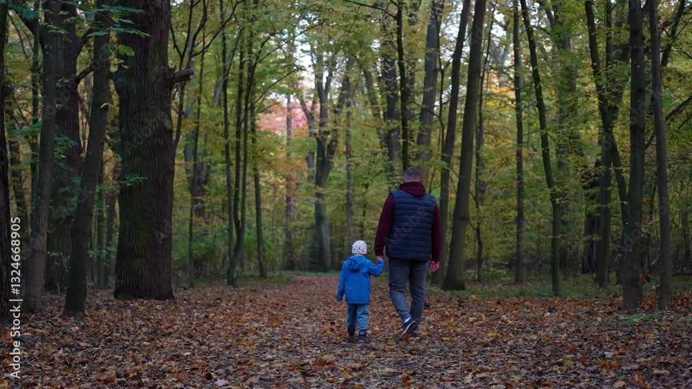 Father and son walking hand in hand on forest path covered with autumn leaves. Concept of family bonding, childhood memories, and outdoor exploration. High quality 4k footage Father and son walking hand in hand on forest path covered with autumn leaves. Concept of family bonding, childhood memories, and outdoor exploration. High quality 4k footage