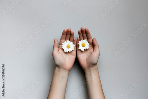 Close-up detail of two clasped hands holding two pure white flowers, on a uniform white background, concept of respect and tolerance