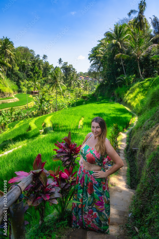 A confident woman stands proudly in a vibrant floral dress amid the stunning rice terraces of Bali, completely surrounded by lush nature and a sense of tranquility, Ubud, Indonesia