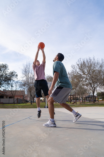 Young caucasian and latin friends playing basketball at the street court
