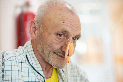 Patient with nasogastric tube on hospital bed waiting for treatment. Positive close up of an elder man waiting for an operation. Enthusiastic approach to hospital treatment..