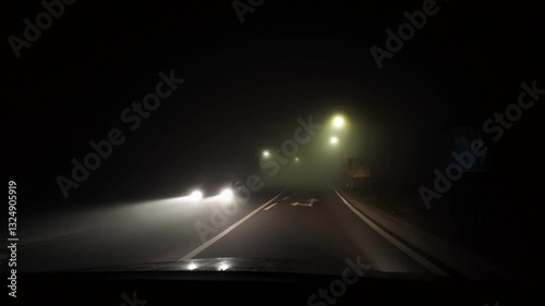 Driving in bad conditions on a foggy road at night. Front car windshield and white beam of lights. Winter weather concept, real time footage with evening lights. Nothing to see on the streets.