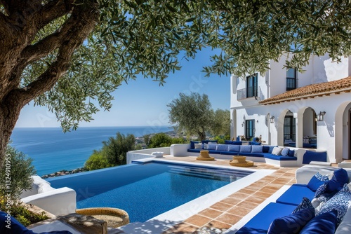 A stunning view of a large Spanish-style villa with whitewashed walls and a sapphire infinity pool, set against the vibrant Mediterranean coast