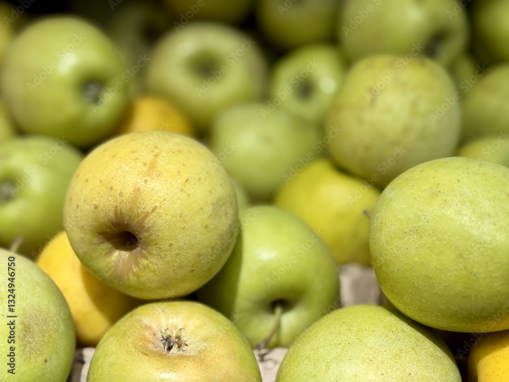 A mound of large green coloured apples in boxes is displayed in the window of the supermarket's vegetable stand, demonstrating organic, vegetarian and healthy food. Close-up A mound of large green coloured apples in boxes is displayed in the window of the supermarket's vegetable stand, demonstrating organic, vegetarian and healthy food. Close-up