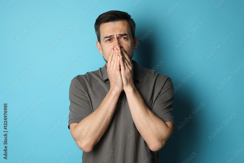 Sad man crying on light blue background Sad man crying on light blue background