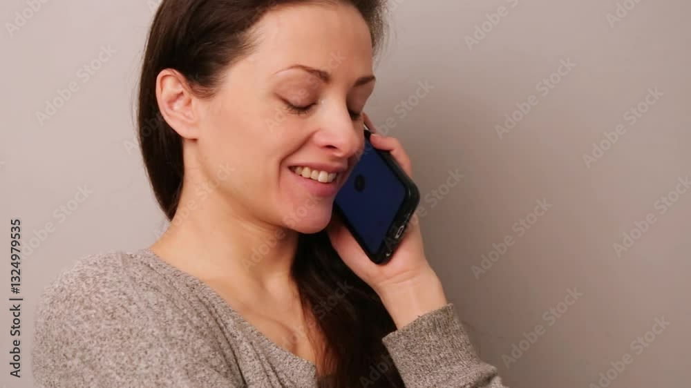 Cute beautiful emotional natural make-up woman with long hair woman talking on mobile phone with happy smiling on neutral background. Closeup video Cute beautiful emotional natural make-up woman with long hair woman talking on mobile phone with happy smiling on neutral background. Closeup video