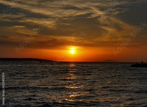 Dramatic summer sky during vivid orange sundown at the seaside