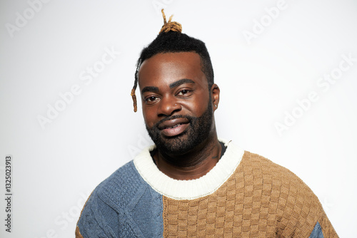 Portrait of a confident Black man in a denim shirt smiling against a white background  
