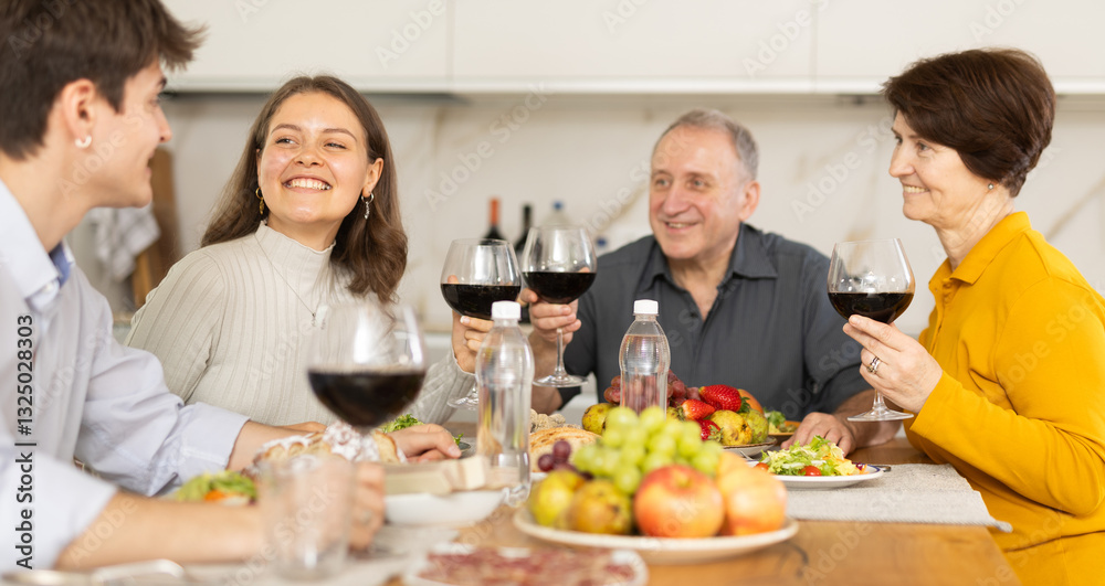 Father and mother together with adult children talking at the dinner table at home Father and mother together with adult children talking at the dinner table at home