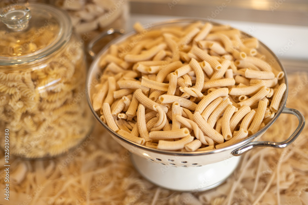Different types of pasta. Many sorts of raw pasta in a cafe, food banner. Uncooked pasta in glass jar and colander, closeup