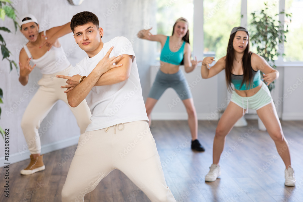 Portrait of cheerful teenage guy practicing krumping movements during group dance lesson in studio