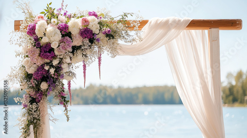 Elegant outdoor wedding arch with purple and white flowers by a lake