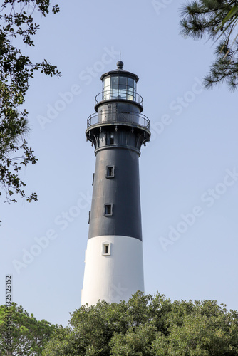 Wallpaper Mural Classic lighthouse standing tall among the treetops against a clear sky Torontodigital.ca