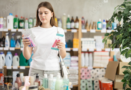 Girl choose product and doubts, faultfinding buyer pick razor kit for allergy sufferers and delicate skin. Customer studies properties of product, checks expiration date