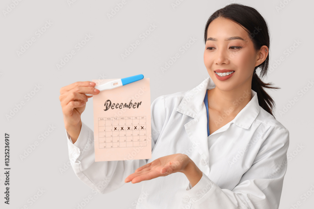 Female Asian doctor with pregnancy test and calendar on light background Female Asian doctor with pregnancy test and calendar on light background