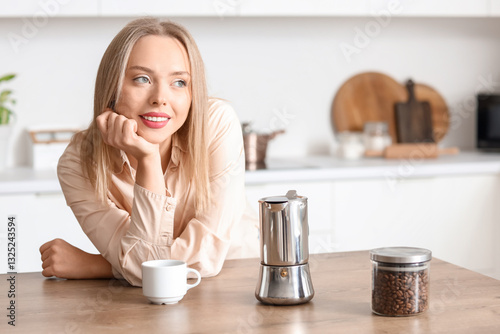 Pretty young woman leaning on wooden table with geyser coffee maker in modern...