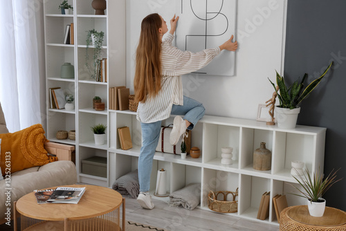 Young woman hanging poster ...