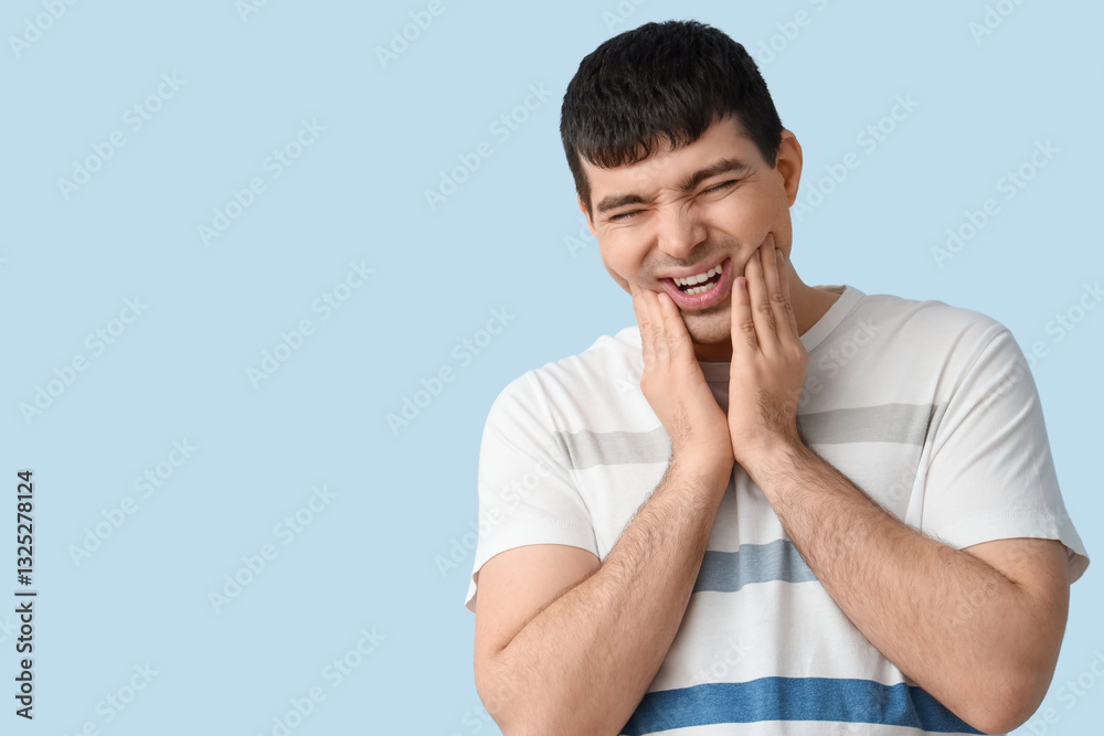 Young man suffering from toothache on blue background, closeup Young man suffering from toothache on blue background, closeup
