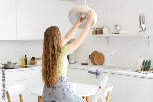 Young woman screwing light ...